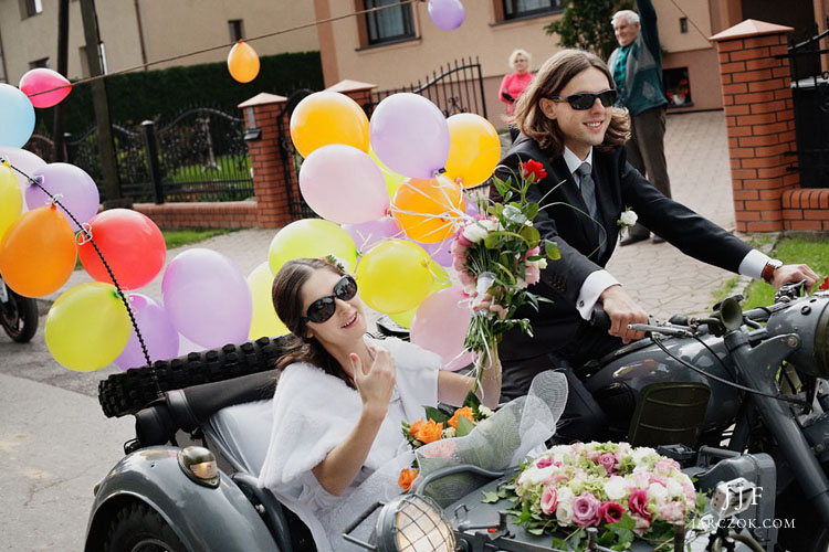 Państwo młodzi jadą do ślubu motocyklem z boczną przyczepą.